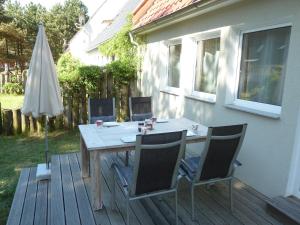 普鲁滕romantisches Ferienhaus Boddenblick mit Sauna的木制甲板配有桌椅和遮阳伞