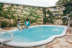 卡纳内亚Pousada Familia Ottoboni的两个年轻人坐在游泳池里