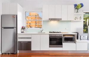 悉尼Breathtaking Sydney Harbour penthouse Enjoy Vivid from your balcony的厨房配有白色橱柜和不锈钢冰箱