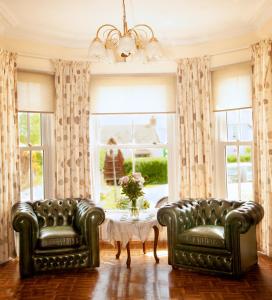 ArdglassBurford Lodge Guest House的窗户间里设有两张皮椅和一张桌子