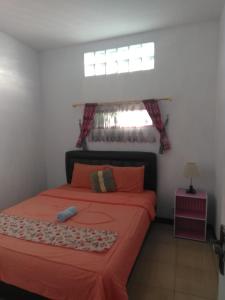 万隆Runia Lembang的一间卧室配有带橙色床单的床和窗户。