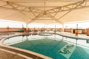 沙迦Red Castle Hotel的一座带遮阳伞的大型游泳池