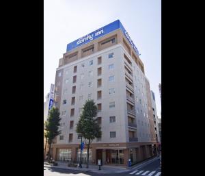 松本多美迎松本酒店的上面有蓝色标志的高大的白色建筑