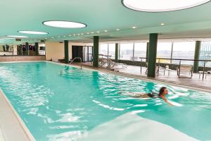 美因河畔法兰克福法兰克福施泰根博阁度假酒店的妇女在建筑物的游泳池游泳