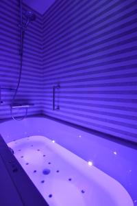 亨法尔马丁迪拉克城堡酒店的紫色照明的客房内的白色浴缸