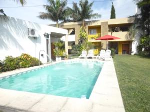 费德拉西翁Las Balsas Hotel的一座带椅子和遮阳伞的别墅前的游泳池