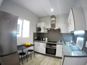 圣克鲁斯-德特内里费Apartamentos Ainara的厨房配有白色橱柜和黑色台面