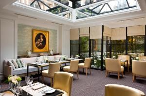 巴黎圣瑞吉斯酒店的一间带桌椅和玻璃天花板的用餐室