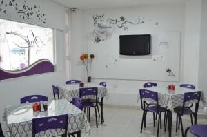 库库塔Hotel Plaza Cúcuta Center的一间带桌椅和电视的用餐室