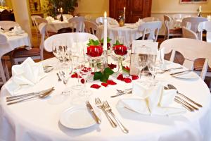 格赖瑙Berghotel Hammersbach的一张桌子上放着白色的桌布和红色的玫瑰