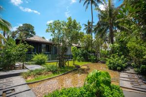 纳泰海滩Baba Beach Club Natai Luxury Pool Villa Hotel by Sri panwa - SHA Plus的一座种植了房屋和棕榈树的花园