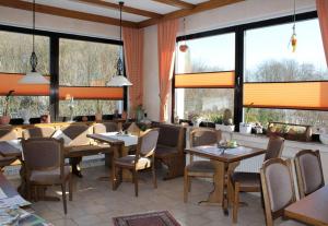梅德巴赫豪斯赫斯贝格酒店的餐厅设有桌椅和大窗户。