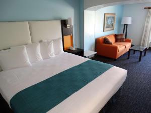 基西米Best Western Plus Orlando Lake Buena Vista South Inn & Suites的酒店客房带一张大床和一把椅子