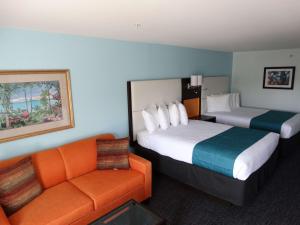 基西米Best Western Plus Orlando Lake Buena Vista South Inn & Suites的酒店客房带两张床和一张橙色沙发