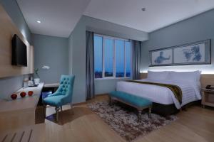 外南梦ASTON Banyuwangi Hotel and Conference Center的一间卧室配有一张床、一张书桌和一个窗户。