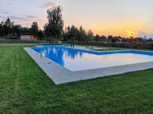 Arpaşu de Sus帕斯特拉瓦利亚阿伯塔度假村的一座位于田野的游泳池,背景是日落