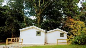 CarrigansDunmore Gardens Log Cabins的两座有树的院子中的白色建筑