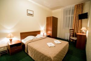 陶格夫匹尔斯Dinaburg SPA Hotel的酒店客房配有一张床、一张桌子和一把椅子。