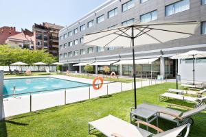 韦斯卡阿巴韦斯卡酒店的一座带椅子和遮阳伞的游泳池位于大楼旁