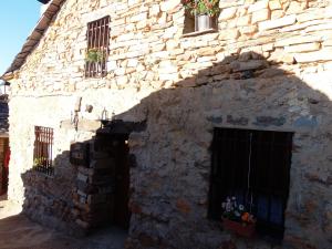 巴尔韦尔德德洛萨罗约斯Casa Rural Los Robles的一座石头建筑,设有两扇窗户和一扇门