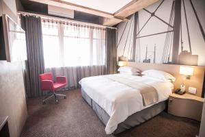 约翰内斯堡里夫酒店的一间卧室配有一张大床和一张红色椅子
