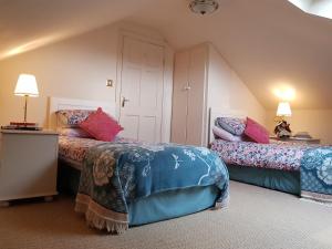 塔洛Grove Cottage at The Lodge的一间卧室配有两张床和两盏灯。
