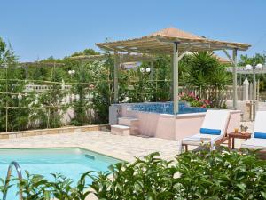 拉加纳斯Three Graces Holiday Houses Complex的一个带两把椅子和遮阳伞的游泳池