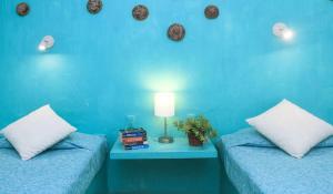 瓦哈卡市唐巴勃罗旅馆的蓝色的客房配有两张床和一张带台灯的桌子