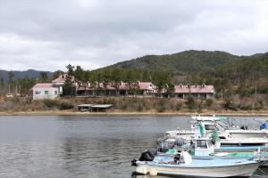 TsudoOkinoshima Resort Island Park Hotel的两艘船停靠在房子前面的水面上