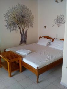斯基亚索斯镇潘申马托拉公寓的卧室配有一张床铺,墙上挂着一棵树