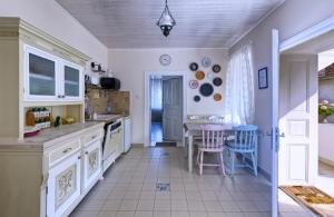 保拉德Ribizli Vintage Vendégház的厨房配有白色橱柜和桌椅
