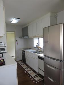 镰仓市镰仓民宿的厨房配有白色橱柜和不锈钢冰箱