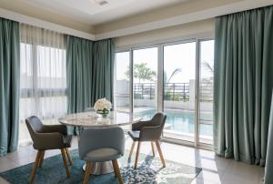 拉斯阿尔卡麦Jannah Hotel Apartments & Villas的一间带桌椅和大窗户的用餐室
