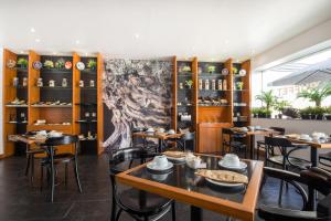 卡帕里卡海岸海和太阳酒店的用餐室配有桌椅,墙上挂有绘画作品