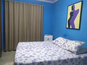 阿拉卡茹Hospedagem Vovó Gina的一间卧室设有蓝色的墙壁和一张带枕头的床