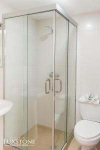 拉巴斯Luxstone Executive & Suites的一间带卫生间的浴室内的玻璃淋浴间