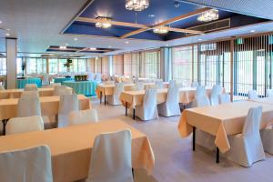 藏王温泉高宫树林酒店的宴会厅配有桌子和白色椅子