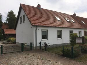 KarnitzFeWo Karnitz/Rügen的白色的房子,有红色的屋顶和栅栏