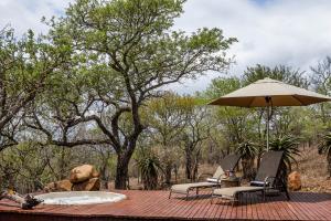 MkuzeMpeti Lodge的甲板上配有一张桌子、一把遮阳伞和两把椅子