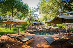 维多利亚瀑布Lokuthula Lodge的庭院内一个带椅子和遮阳伞的游泳池