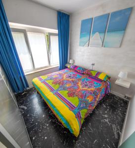 加尔达湖滨思丽维公寓的一间卧室配有一张带五颜六色棉被的床