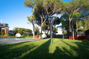 SelcettaRelais Villa Italia的绿意盎然的草坪上种满了树木,设有游泳池
