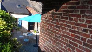 GuiseChez Louise的蓝色的伞,坐在砖墙旁边