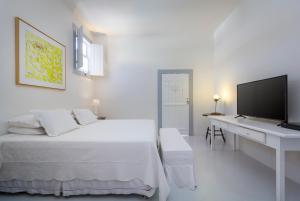 帕拉蒂Pousada Casa de Paraty的白色卧室配有一张床和一张书桌及电视