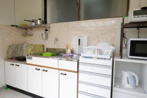 屋久岛古太郎度假屋的厨房配有白色橱柜和微波炉