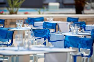 耶奥伊乌波利斯神话宫殿Spa度假村的一组桌子,配蓝色椅子和酒杯