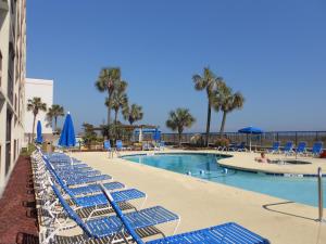 默特尔比奇Ocean Club Resort Myrtle Beach a Ramada by Wyndham的一个带蓝色躺椅的游泳池和一个游泳池