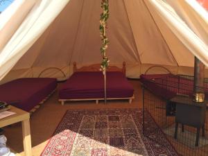 南安普敦Bell Tent Glamping at Royal Victoria Country Park的一个带两张床的帐篷和一个地毯