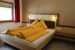 朗根费尔德Haus Alpina & Landhaus Schöpf的一间卧室配有一张带黄色毯子和枕头的床