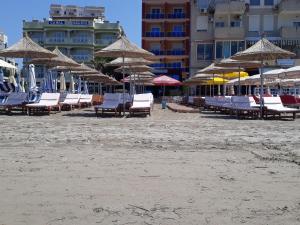 都拉斯Hotel 3 Vellezerit的海滩上的一组椅子和遮阳伞